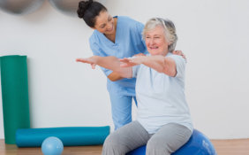 caregiver assisting senior woman in her exercise