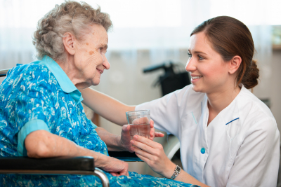 caregiver giving water to a senior woman